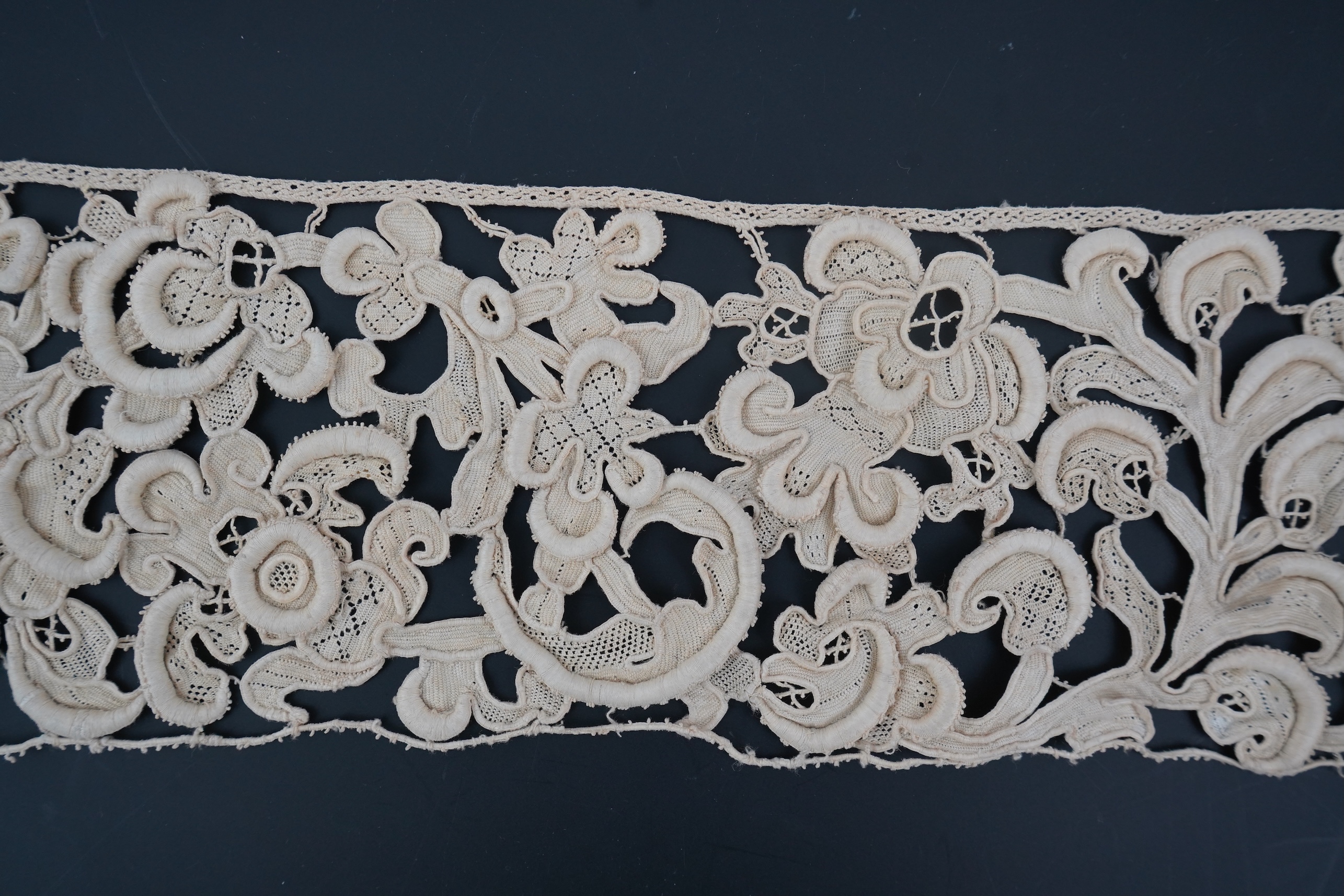 A length of 1660-1670 Italian Venetian Gros Point needle lace, this heavy needle lace was made with a wide cordonnet padded with wool, using close buttonhole stitch, to create large scrolling patterns in heavy relief, li